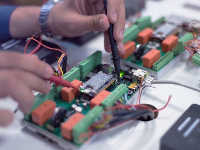 close-up of hands working on a circuit control board