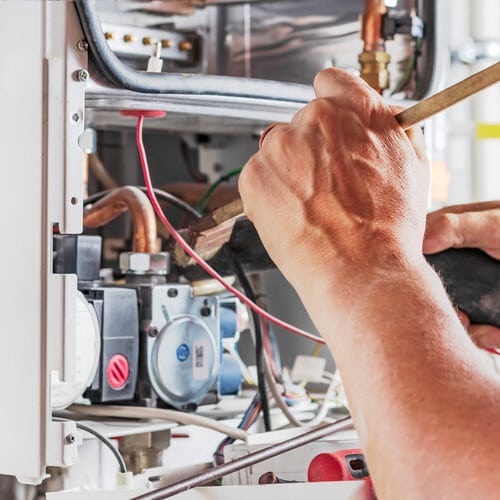 The master sets up a gas boiler, which weighs on the wall. The front dashboard is open. Using a brush and an industrial vacuum cleaner, cleaning from dirt and dirt