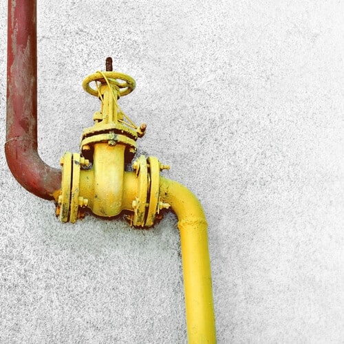 The picture shows Yellow gas pipe with a valve on the wall of building. There is a place for the text box.